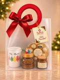 Ancheta de lujo navideña con taza, café, vela aromática y chocolates en bolsa de regalo con moño rojo – Salva Flores y Regalos