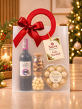 Ancheta de lujo navideña con vino tinto, chocolates, macadamias y frutos secos en bolsa de regalo con moño rojo – Salva Flores y Regalos
