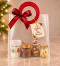 Ancheta navideña con taza Feliz Navidad, café, macadamias y frutos secos en bolsa de regalo con moño – Salva Flores y Regalos